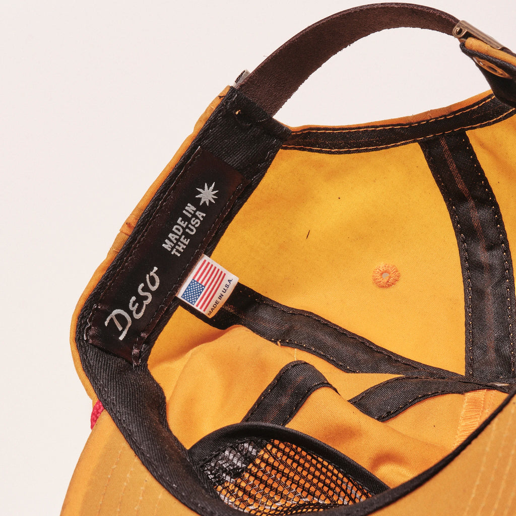 Yellow cap with black strap and 'Deso' branding on a white background