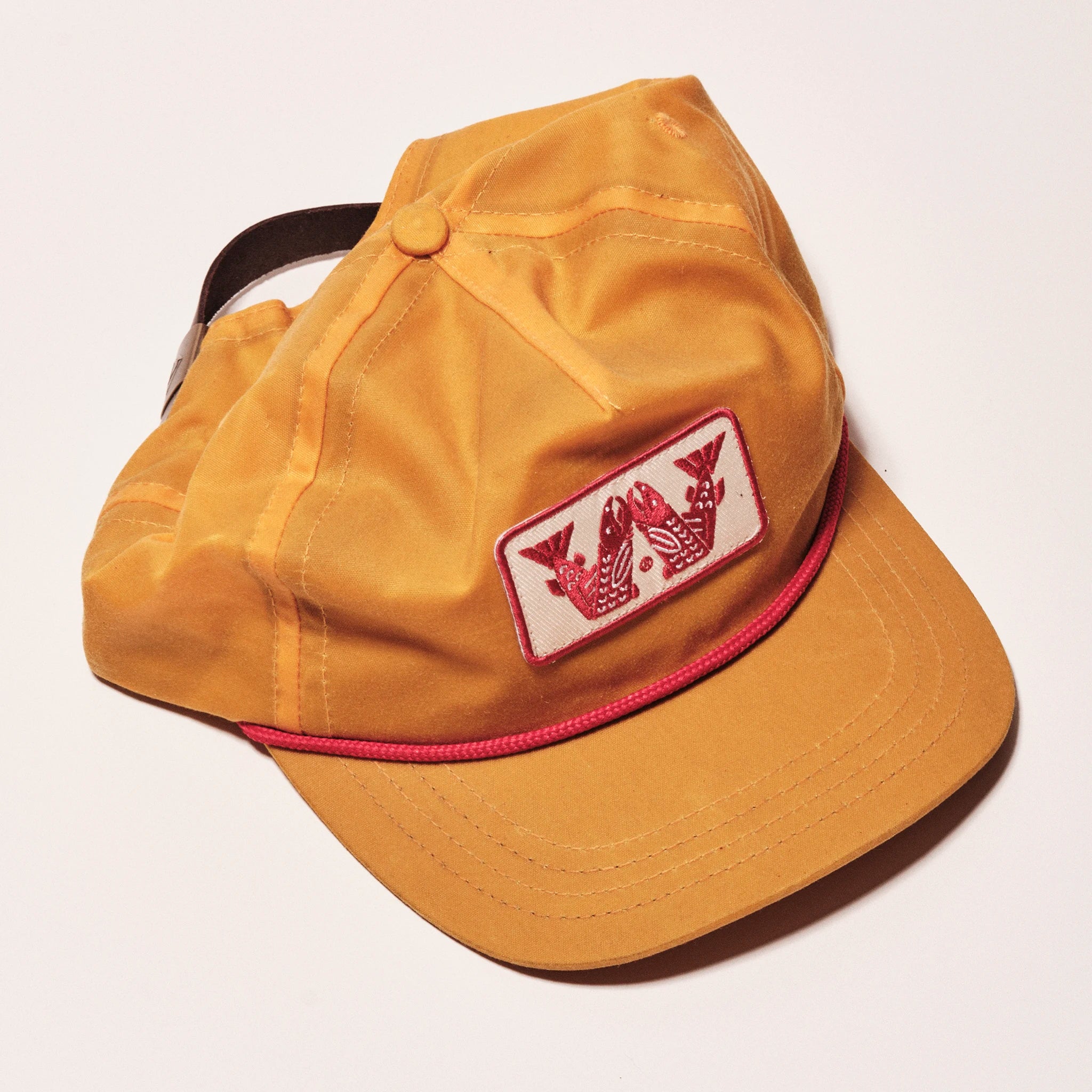 Yellow cap with a red and white logo on a light gray background