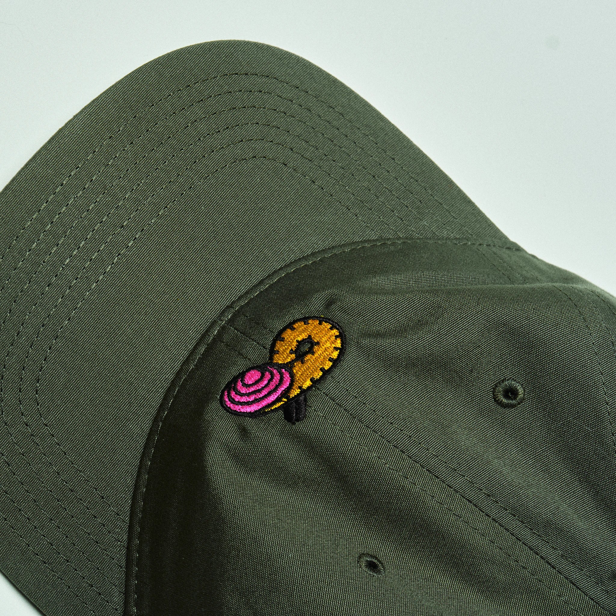 Green cap with a colorful embroidered design on a light gray background