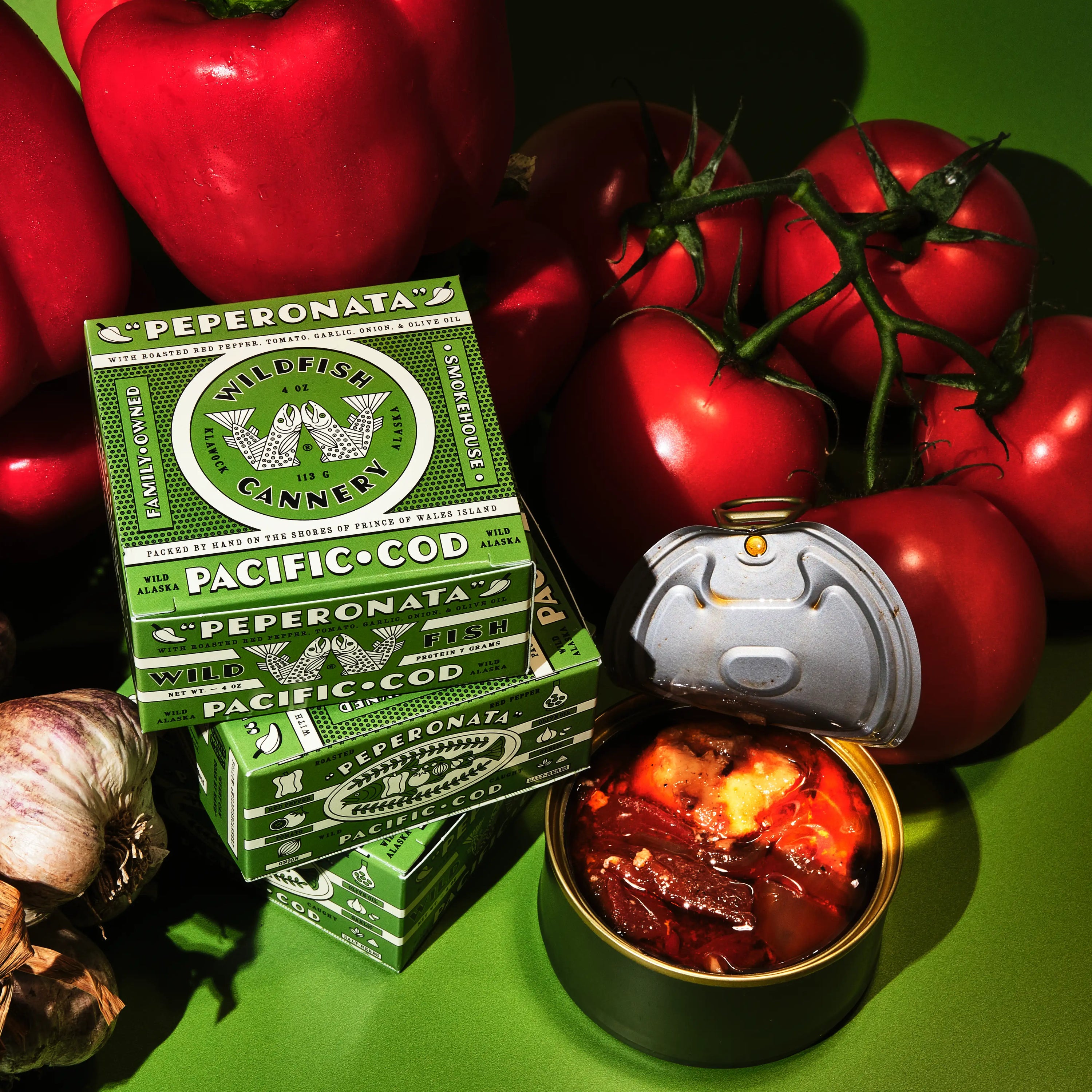 Product photo with open can surrounded by vegetables on green background