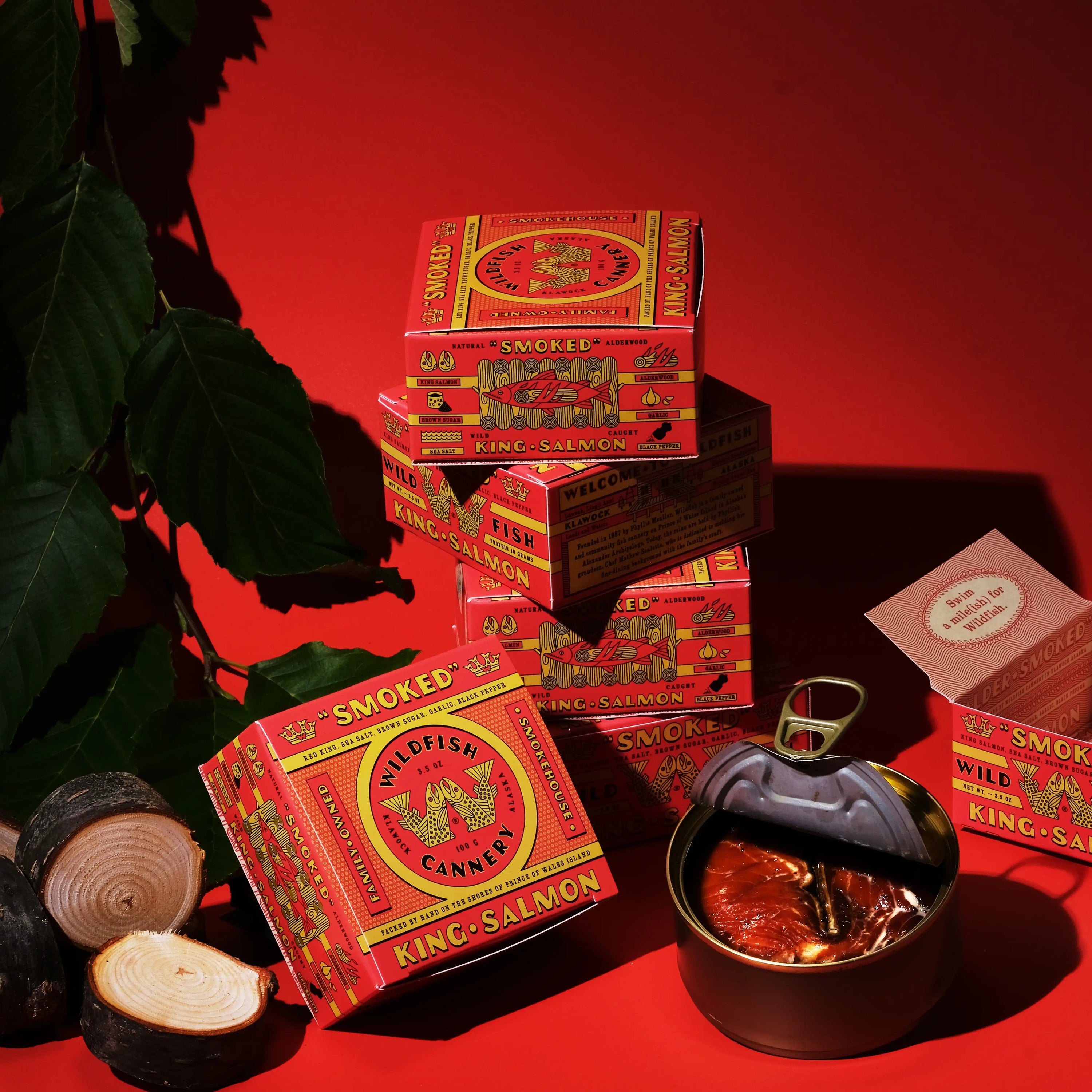 Several red and yellow products boxes on red background with open can with fish inside