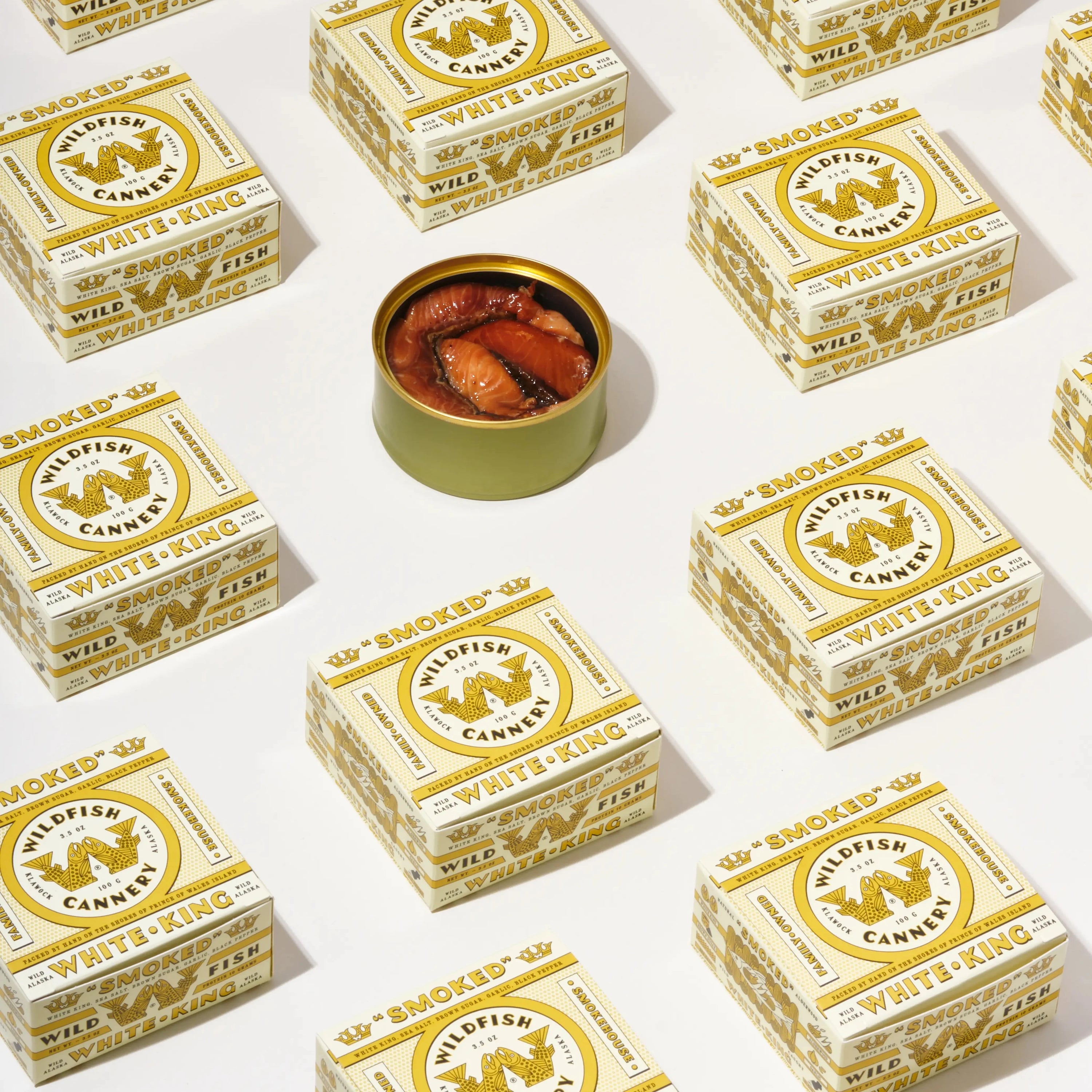 Assembly of white and gold boxes with open can of fish in center on white background