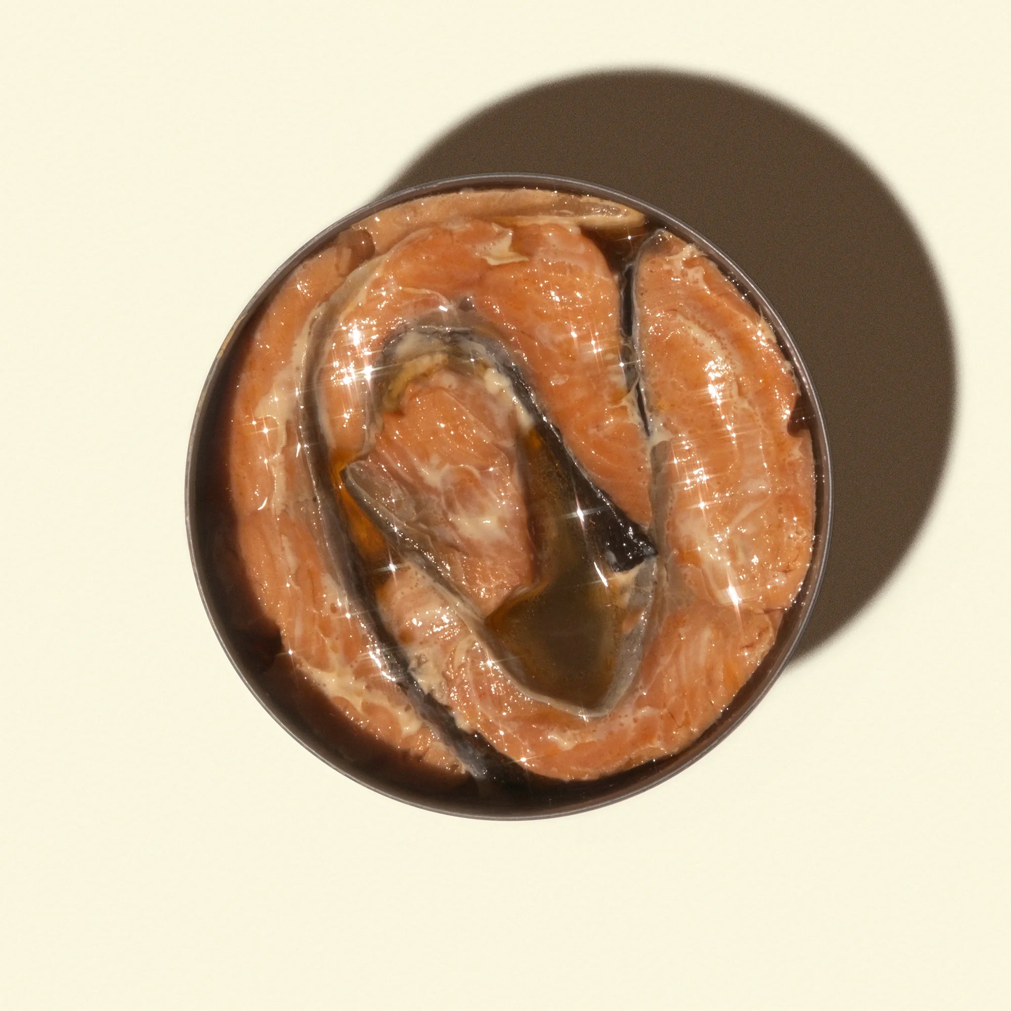 Open can of fish on a beige background