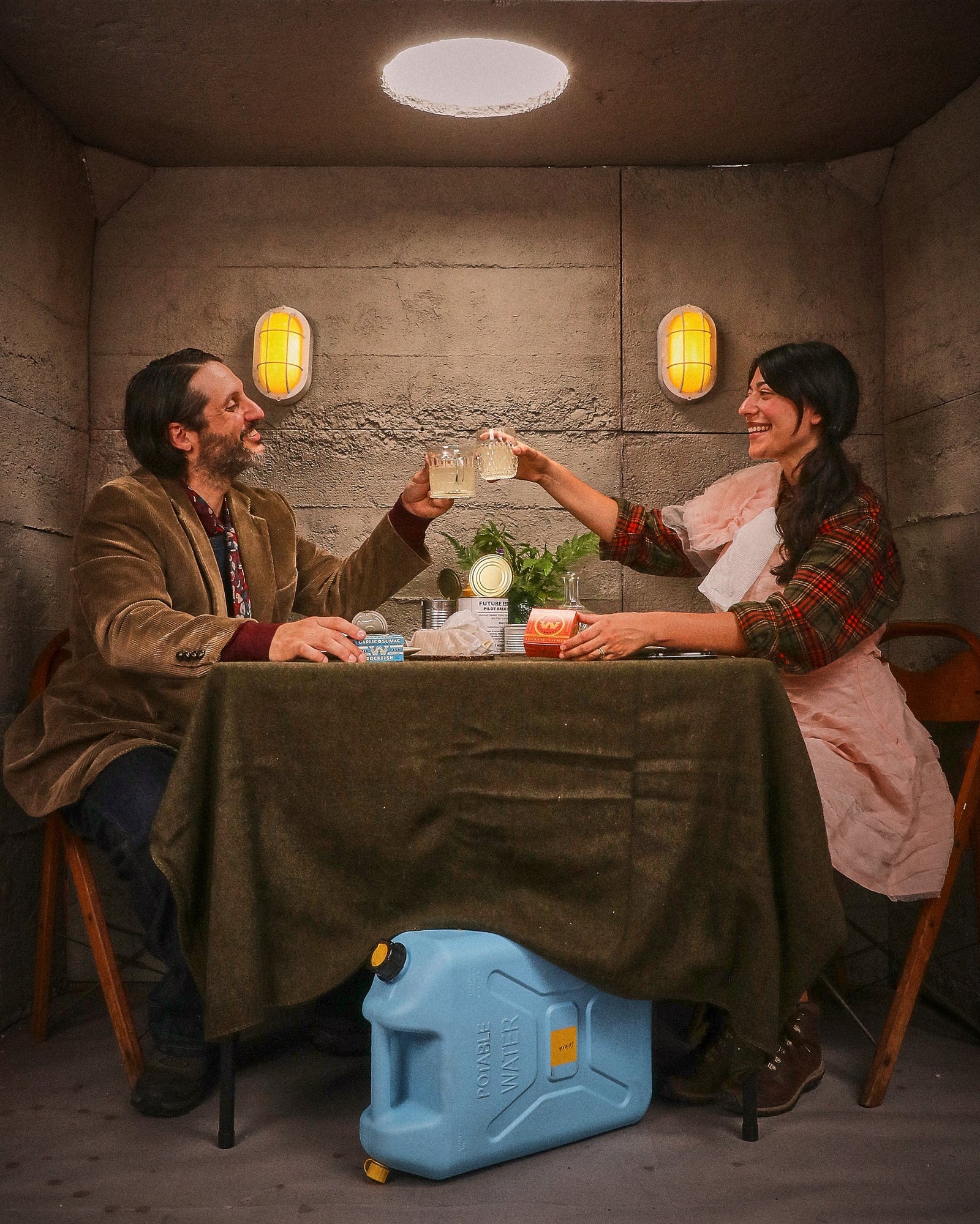 The couple clink glasses across the table, a blue water jug tucked beneath it.